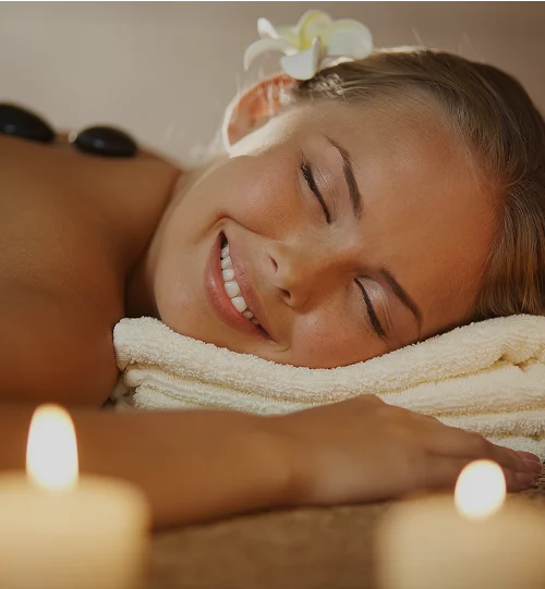 Femme allongée sur une serviette recevant un massage aux pierres chaudes sur le dos dans un spa